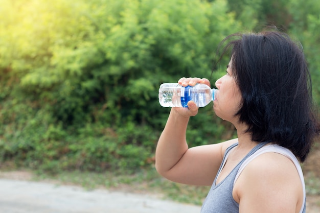 Asian woman drinking water after sport exercise,sport woman holding bottle of pure water