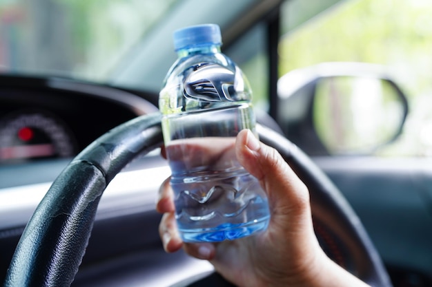 Asian woman driver hold cold water for drink in car dangerous and risk an accident