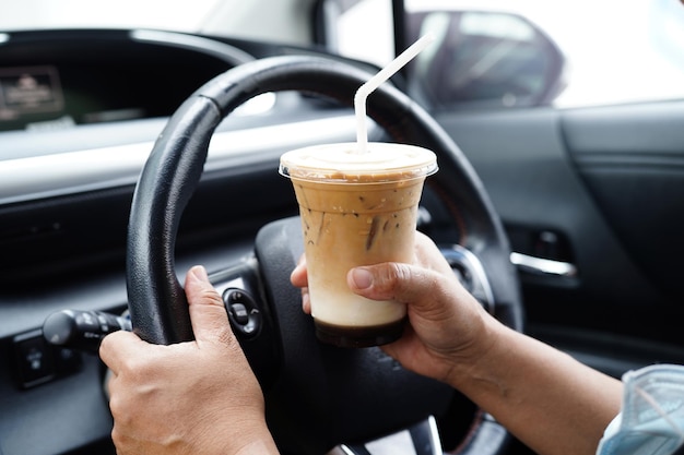 Asian woman driver hold ice coffee cup for drink in car dangerous and risk an accidentxA