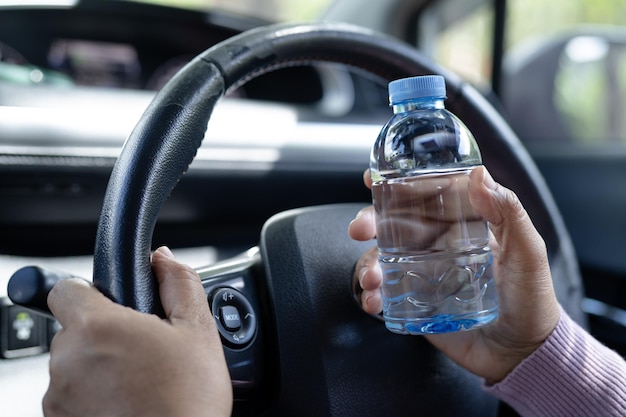 Asian woman driver holding bottle for drink water while driving a car Plastic hot water bottle cause fire