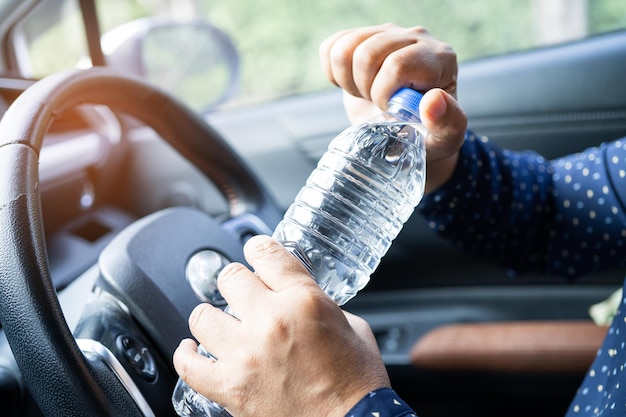 Asian woman driver holding bottle for drink water while driving a car Plastic hot water bottle cause fire