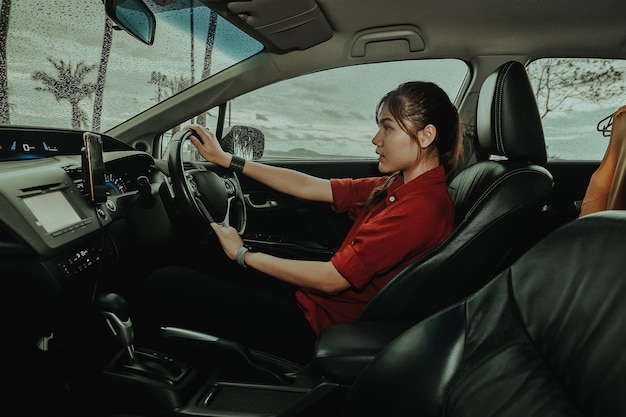 Asian woman driving car attractive girl sitting in automobile outdoors raining