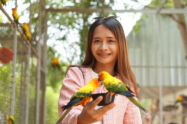 Asian woman feeding parrots in the garden