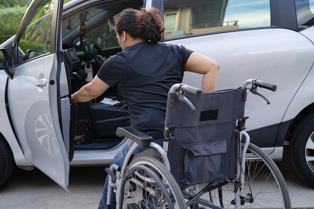 Asian woman folding and lift up wheelchair into her car. Accessibility concept.