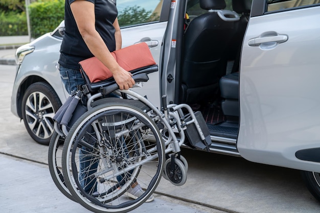 Asian woman folding and lift up wheelchair into her car Accessibility concept