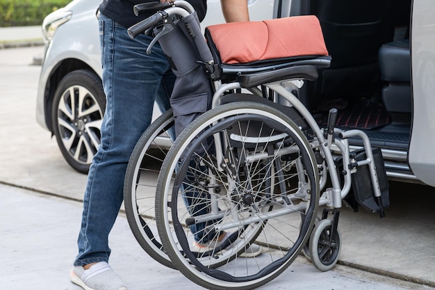 Asian woman folding and lift up wheelchair into her car Accessibility concept