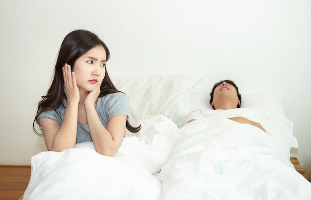 Asian woman getting disturbed and annoy with man sleep and snoring on bed