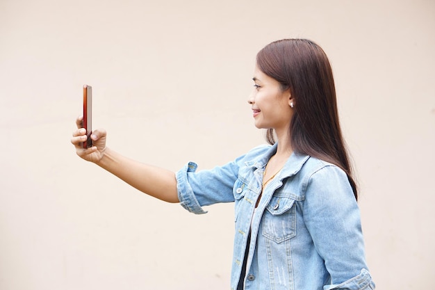 Asian woman happily takes a selfie with her phone