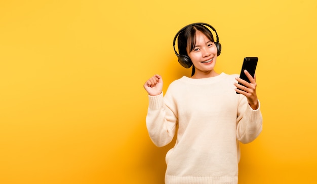 Asian woman happily using the phone and listening to music Relaxing with music. On a comfortable day. Dance and relaxation concept. listening to music online