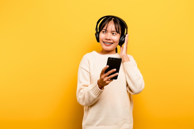 Asian woman happily using the phone and listening to music Relaxing with music On a comfortable day Dance and relaxation concept listening to music online