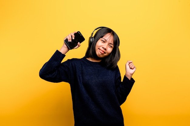 Asian woman happily using the phone and listening to music Relaxing with music On a comfortable day Dance and relaxation concept listening to music online