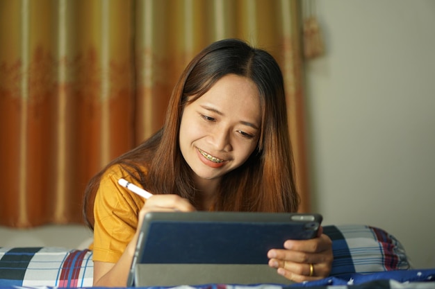 Asian woman happy after watching profit from computer on the bed working from home