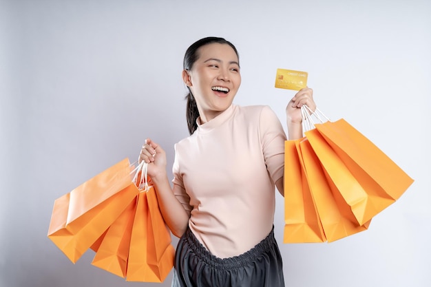 Asian woman happy smiling holding shopping bags and credit card isolated over white background