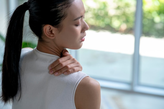 Asian woman has neck and shoulder pain Female holding painful neck with another hand People with bodymuscles problem Healthcare And Medicine