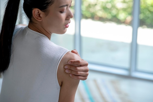 Asian woman has shoulder pain Female holding painful shoulder with another hand People with bodymuscles problem Healthcare And Medicine