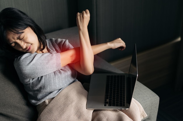 Asian woman has shoulder pain while working on laptop at home People with bodymuscles problem Healthcare And Medicine