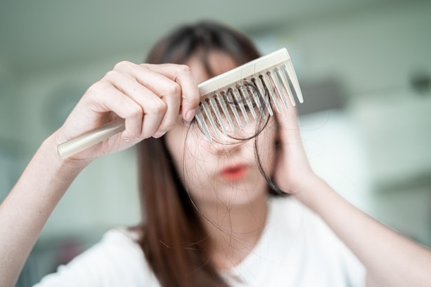 Asian woman have problem with long hair loss attach to comb brush