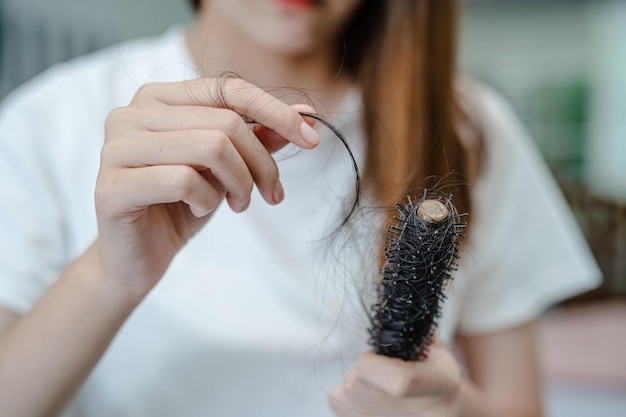 Asian woman have problem with long hair loss attach to comb brush