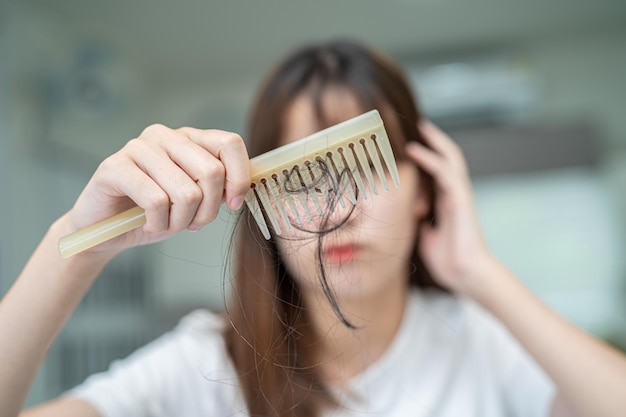 Asian woman have problem with long hair loss attach to comb brush