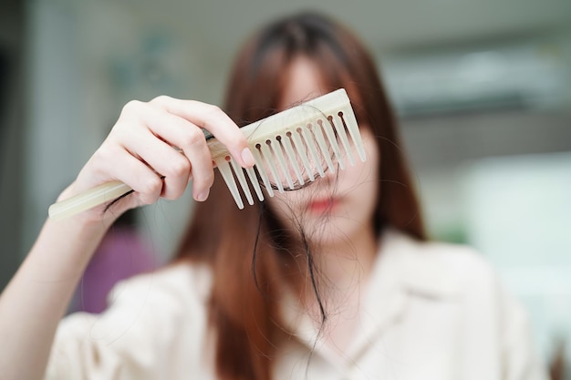 Asian woman have problem with long hair loss attach to comb brush