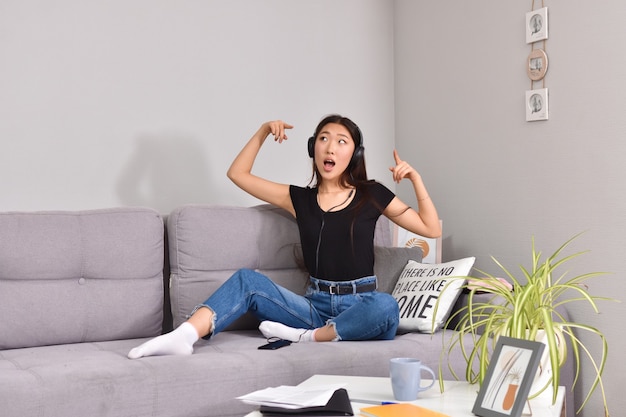 Asian woman in headphones using smartphone