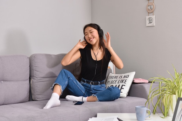 Asian woman in headphones using smartphone