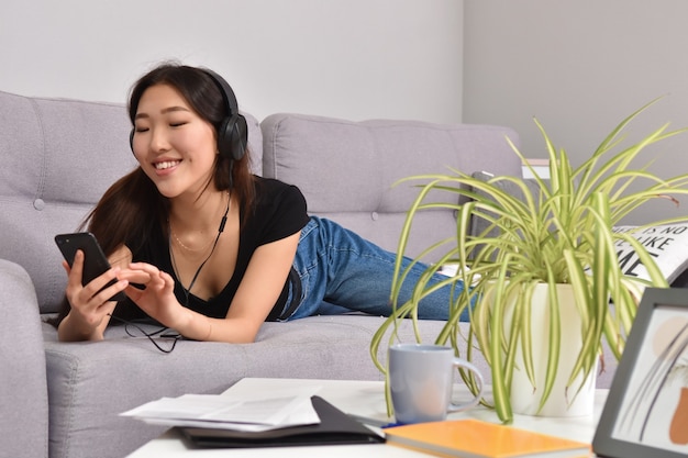 Asian woman in headphones using smartphone