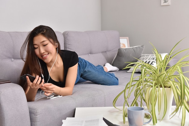 Asian woman in headphones using smartphone