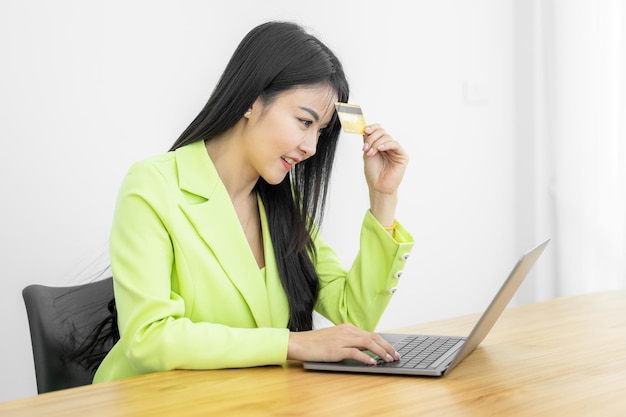 Asian Woman holding bank business credit card with computer laptop Woman hand holding bank credit card Paying using credit card Asian shopaholic shopping online lifestyle