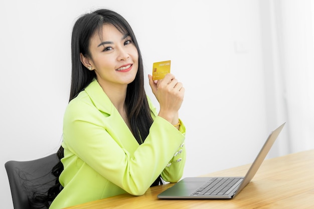 Asian Woman holding bank business credit card with computer laptop Woman hand holding bank credit card Paying using credit card Asian shopaholic shopping online lifestyle