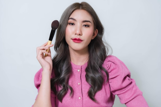 Asian woman holding a blush brush Concept photo of a beautiful Asian makeup artist