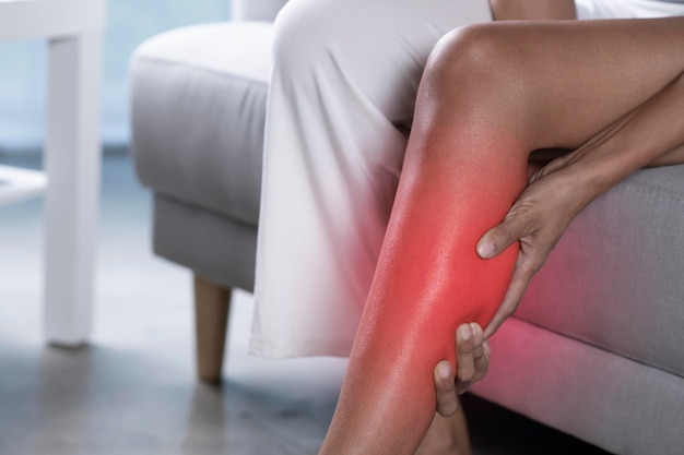 Asian woman holding the calf with pain Closeup image of female suffering from pain in leg at home Health care concept