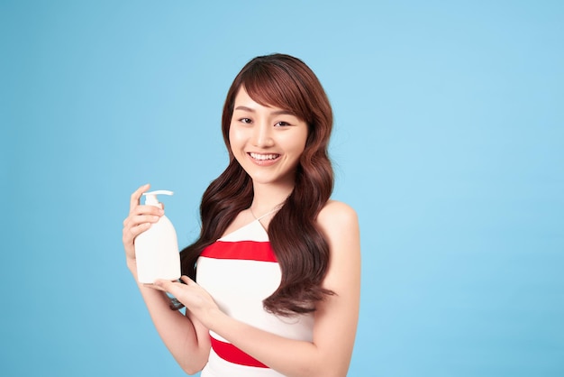 Asian woman holding cosmetic bottle and smile isolated on white background