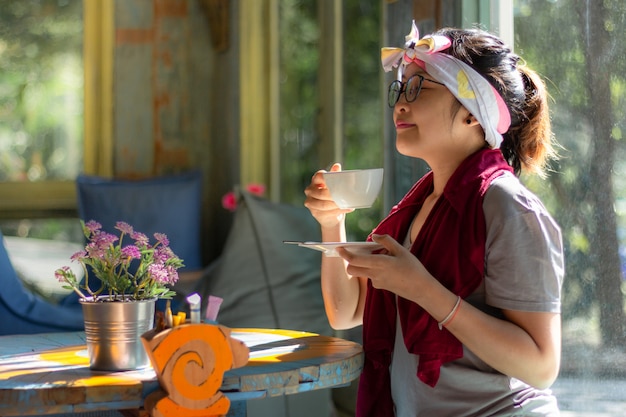 Asian woman holding and drinking a cup of coffee 