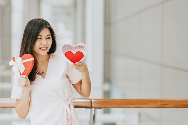 Asian woman holding gift box with red heart 