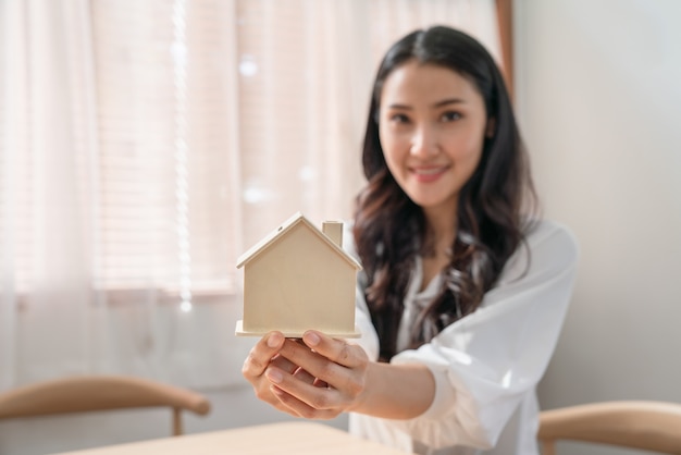 Asian woman holding home model