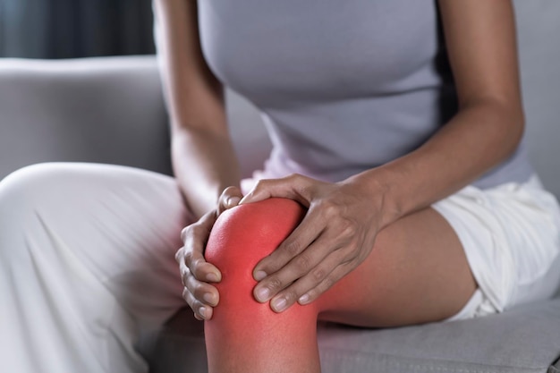 Asian woman holding the knee with pain Female suffering from pain in leg at home Health care concept