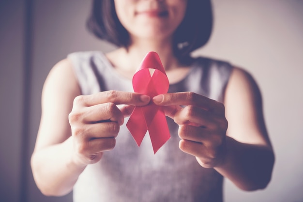 Asian woman holding pink ribbon, breast cancer awareness