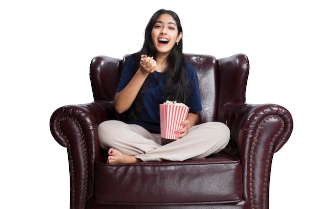 Asian woman holding a popcorn sitting on the couch