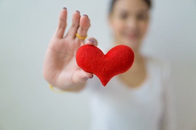 Asian woman holding a red heart in her hands.