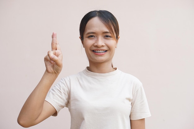 Asian woman holding two fingers crossed