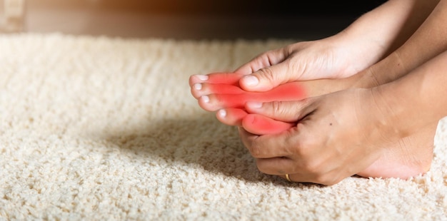 Asian woman holds her toe injury feeling pain her foot at home