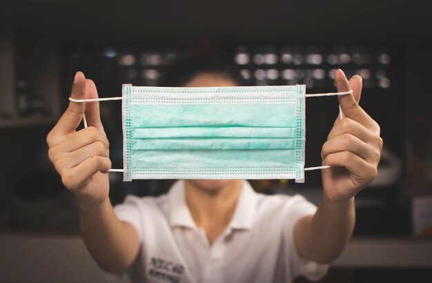 Asian woman holds a medical mask on hand for wearing on the face to against infection coronavirus,Covid-19 prevention.