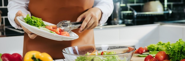 Asian woman is pouring ingredients that are prepared to make a salad into a salad bowl