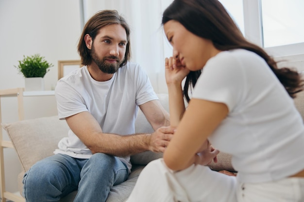 An Asian woman is sad and crying with her male friend at home Stress and misunderstanding in a relationship between two people and supporting each other39s mental and emotional wellbeing