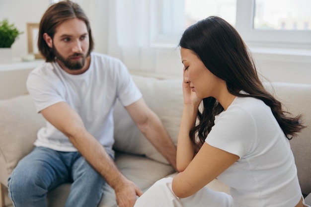 An Asian woman is sad and crying with her male friend at home Stress and misunderstanding in a relationship between two people and supporting each other39s mental and emotional wellbeing