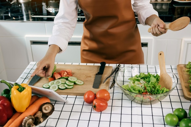 Asian woman is searching for a recipe website for cooking on a tablet in the kitchen