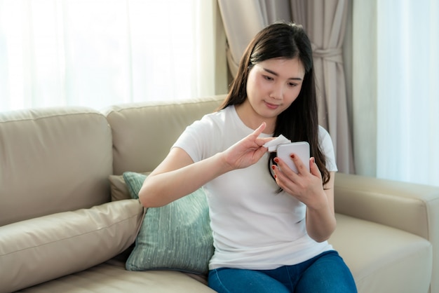 Asian woman is spraying alcohol on mobile phone