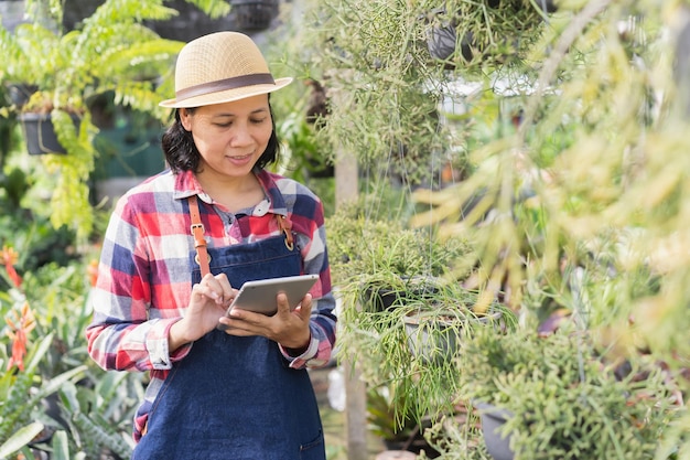 Asian woman is using a tablet to check the vegetation in the Ornamental plant shop Small business concept