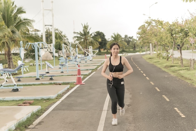 Asian woman jogging in the parklisten music with runninghappy woman love heathy